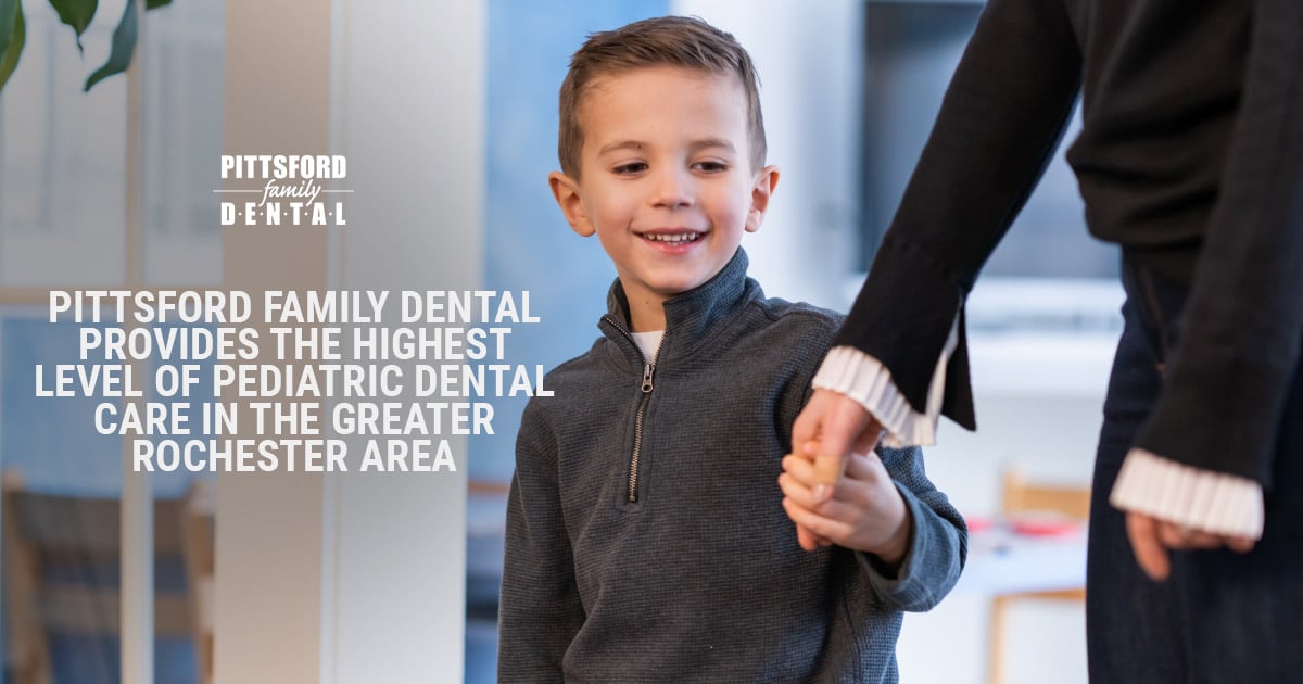 Young boy smiling while holding adult's hand in modern dental office setting.