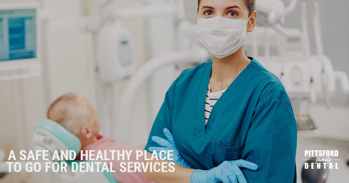 Dental hygienist in blue scrubs and mask holding child in modern dental office setting.