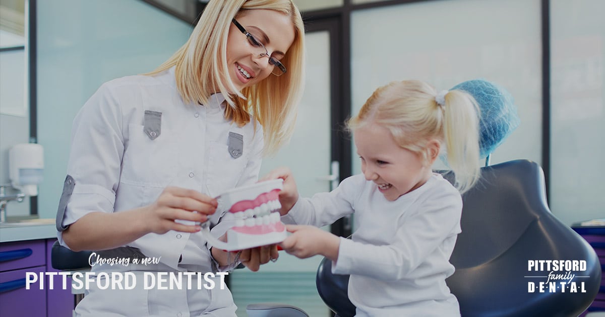 Female dentist showing young child a dental model in modern office setting.