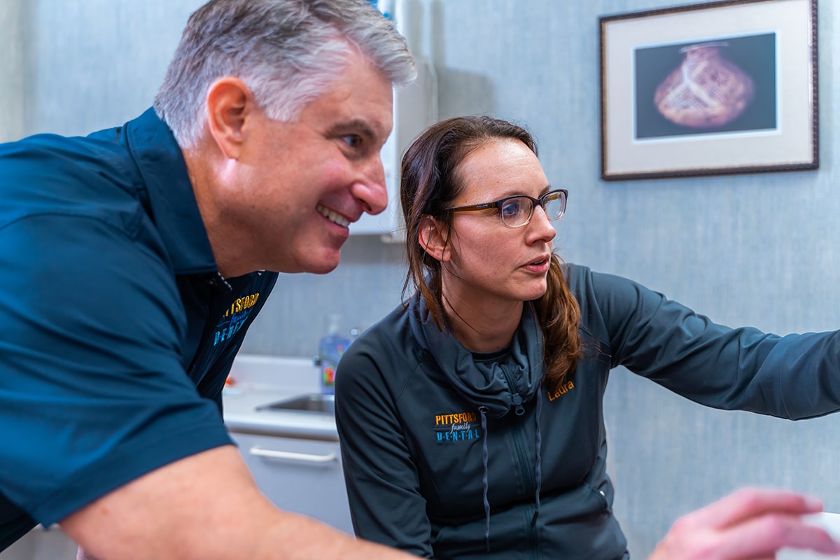 Two dental professionals in scrubs discussing patient care in a clinical office setting.