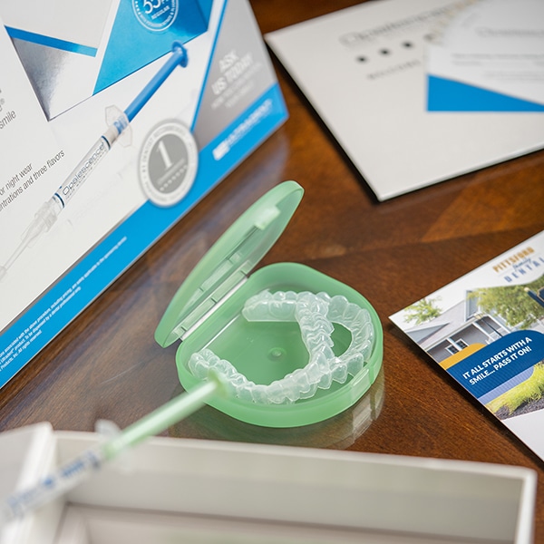 Clear aligners and dental marketing materials displayed on wooden desk in dental office setting.
