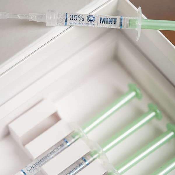 Dental syringe containing 35% mint-flavored local anesthetic in organized storage tray.