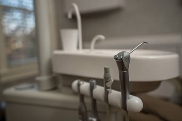 Dental instruments and tools arranged on counter in modern dental office bathroom setting.