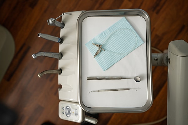 Dental instruments and tools arranged on a tray with blue gauze in a dental office setting.