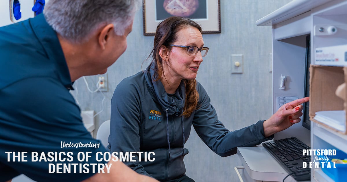 Female dentist in scrubs explains cosmetic dentistry to patient in dental office at Pittsford Family Dental.