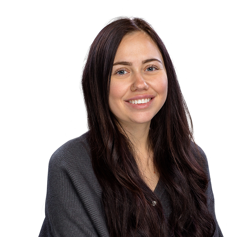 Professional headshot of smiling woman in dark top against white background, dental office staff portrait.