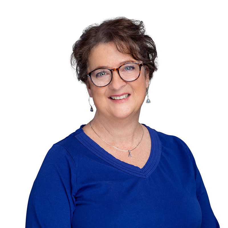 Professional headshot of a woman wearing glasses and blue v-neck shirt against white background.