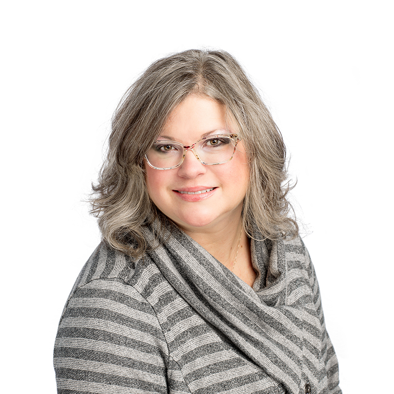 Professional headshot of woman with gray hair and glasses wearing striped gray blazer against white background.