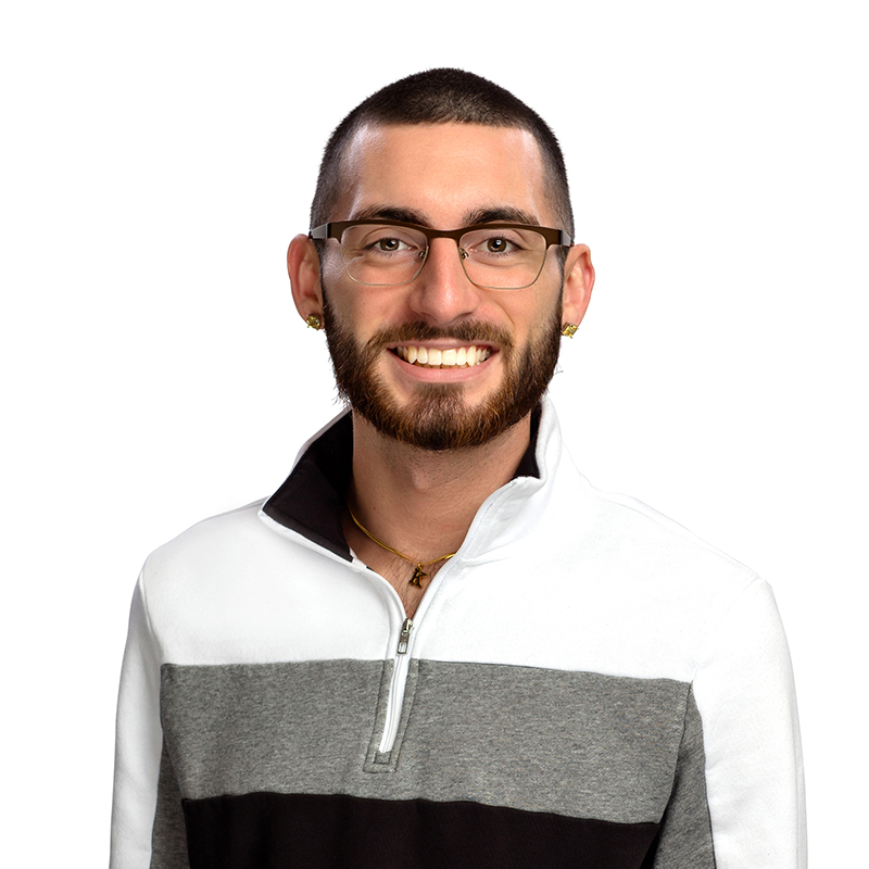 Smiling man wearing glasses and striped pullover against white background, professional headshot.