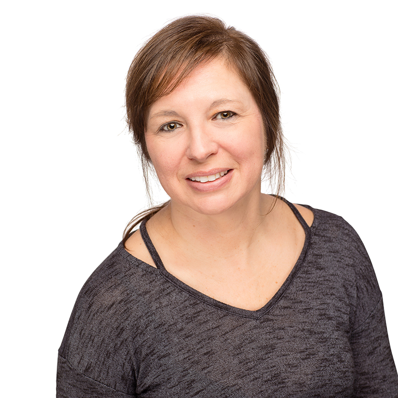 Professional headshot of smiling woman in gray shirt against white background.