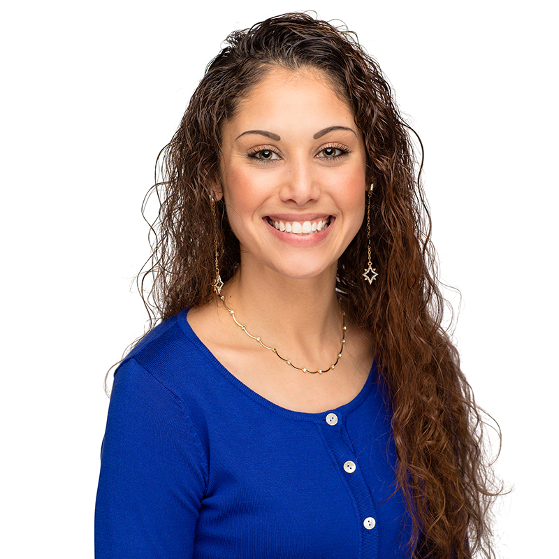 Professional headshot of smiling woman with long brown hair wearing blue top and star earrings.