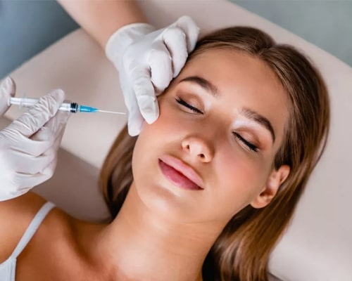 Woman receiving cosmetic injection treatment from gloved healthcare professional in clinical setting.